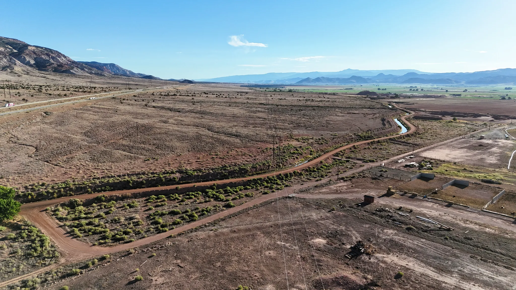 Expansive land parcel featuring natural terrain, distant mountains, and established roadways