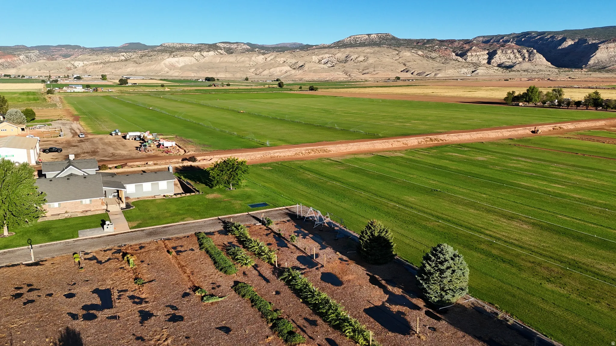 Expansive property featuring structured landscaping, a manicured lawn area, and visible agricultural fields
