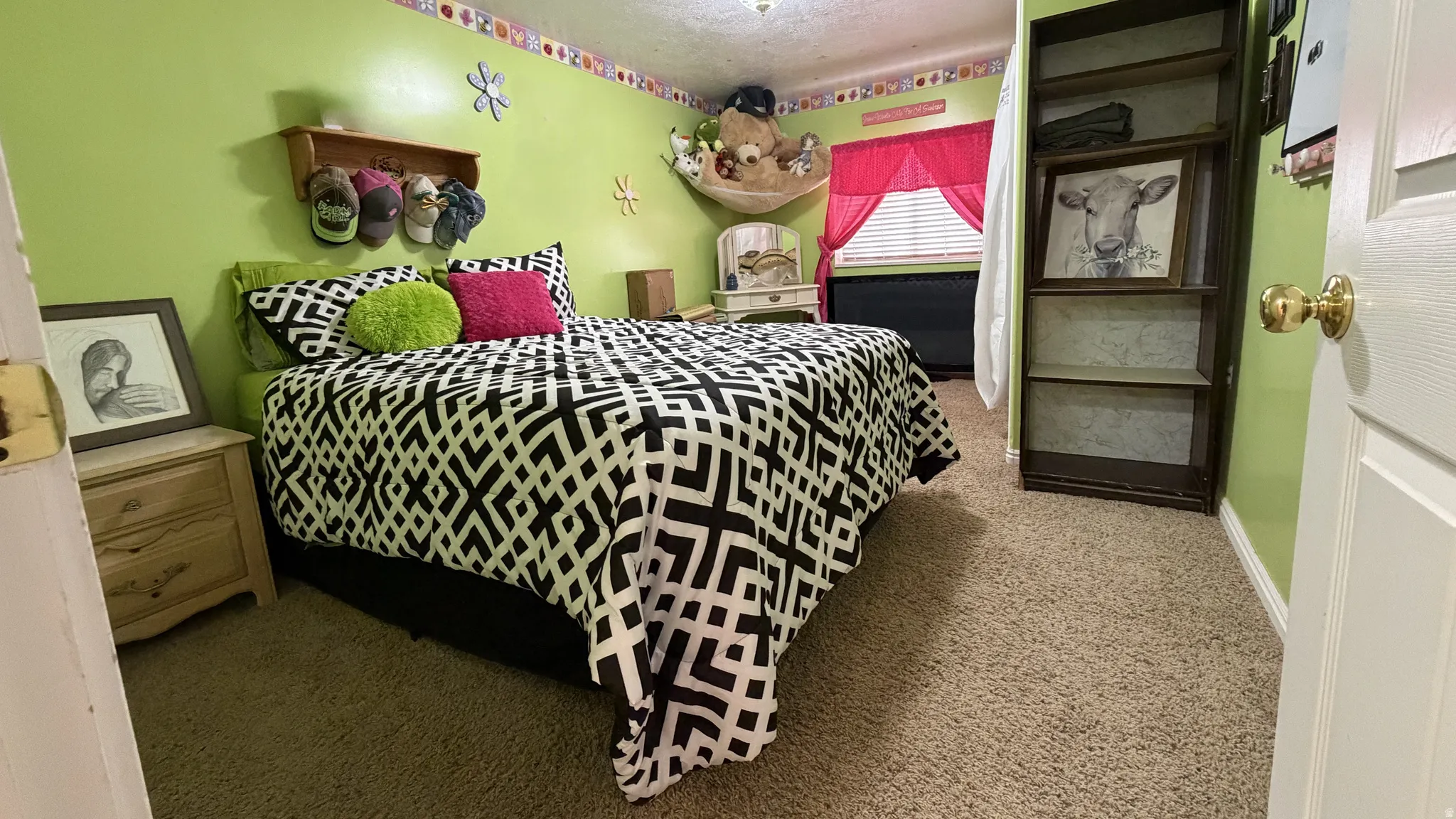Carpeted room featuring light green walls, a built-in shelving unit, and a window with blinds