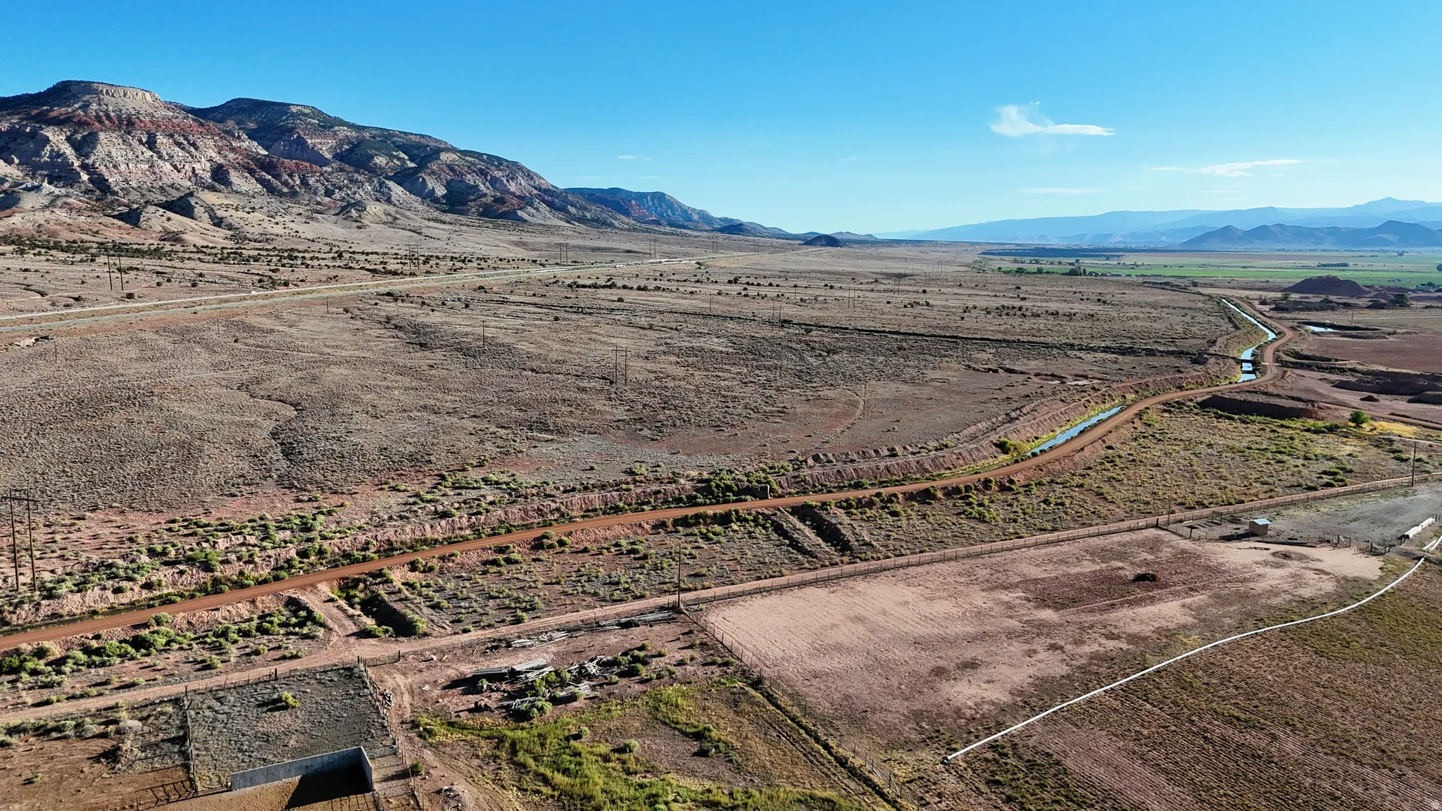 Expansive desert landscape featuring distant mountains and an irrigation canal