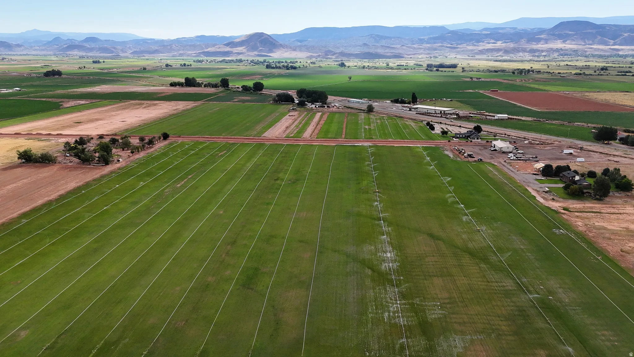 Expansive agricultural fields with irrigation lines and distant mountain scenery