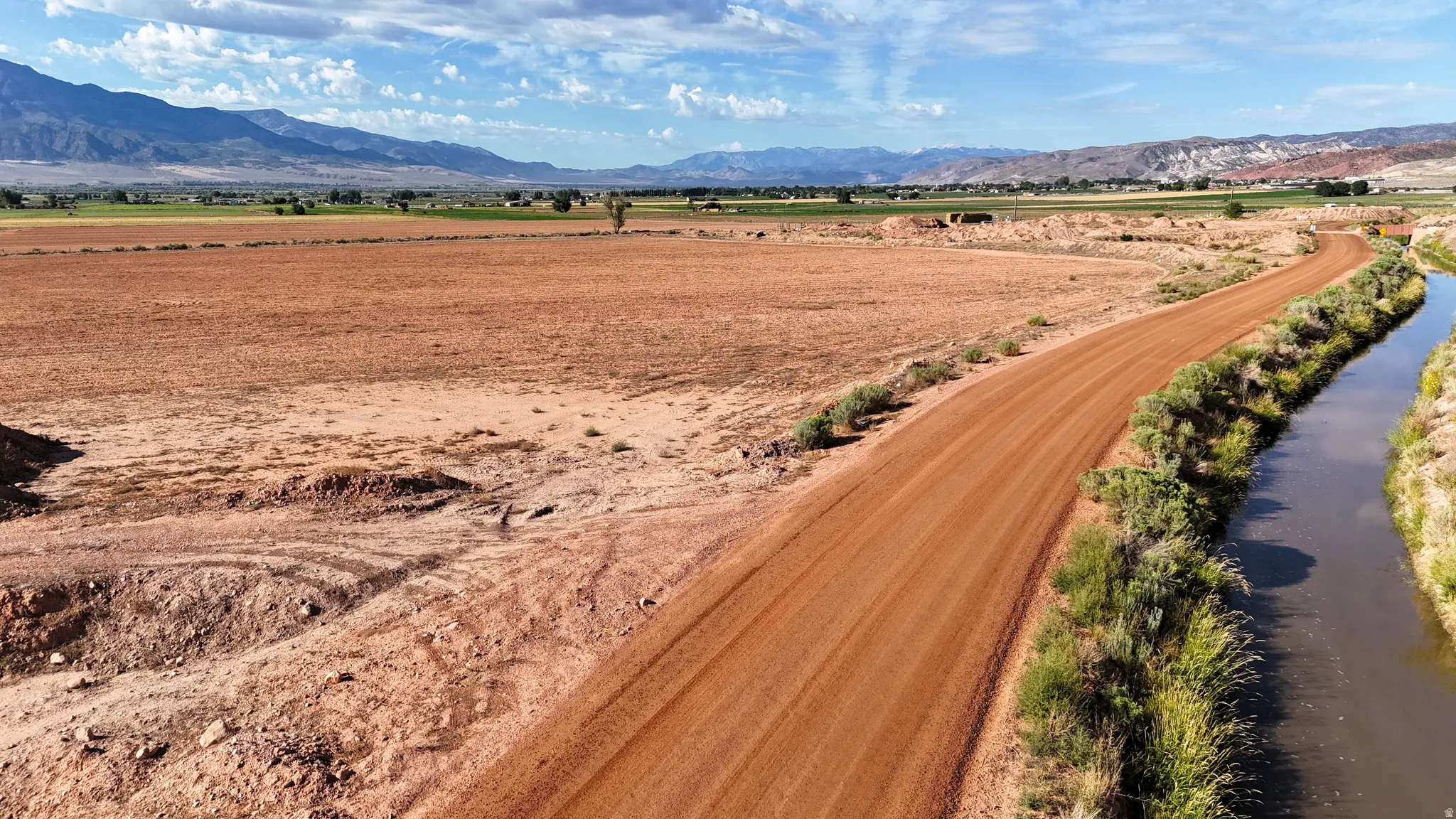 Expansive land parcel with a dirt road and adjacent waterway