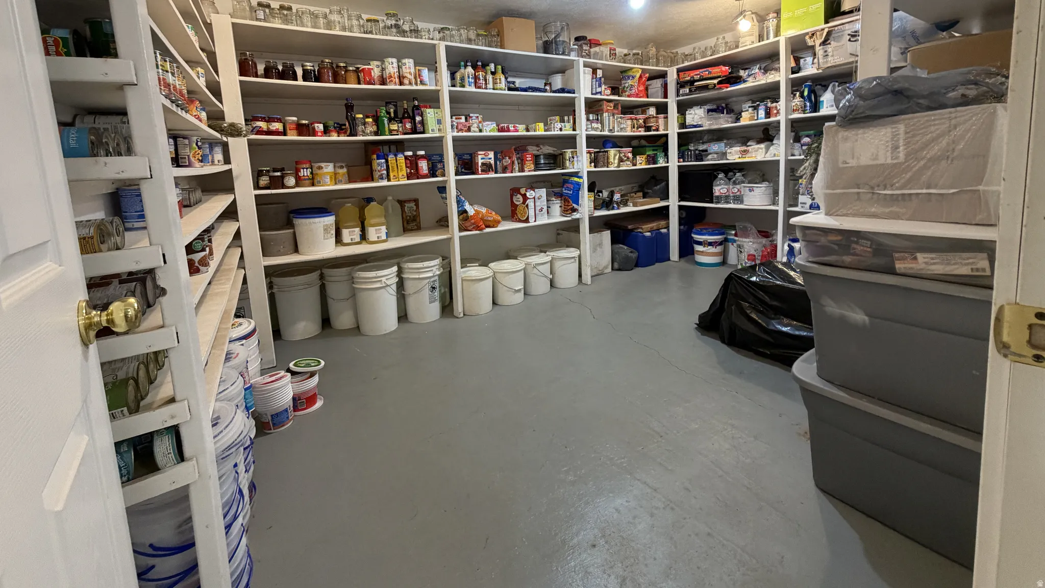 Spacious storage area featuring extensive built-in shelving, durable flooring, and a solid entry door