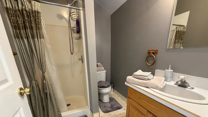 White shower enclosure with a chrome shower head and integrated storage