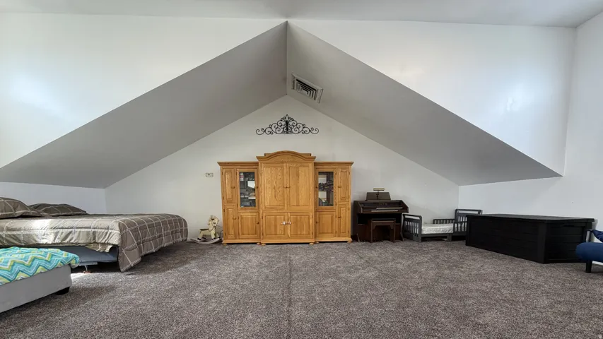 Vaulted ceilings with exposed beams, recessed lighting, and soft gray carpeting