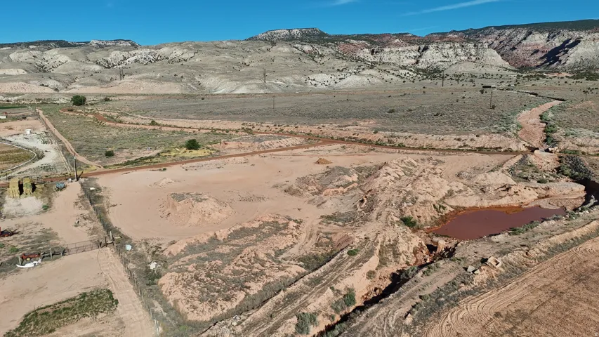 Expansive land parcel with graded terrain, a natural waterway, and distant mountain backdrops