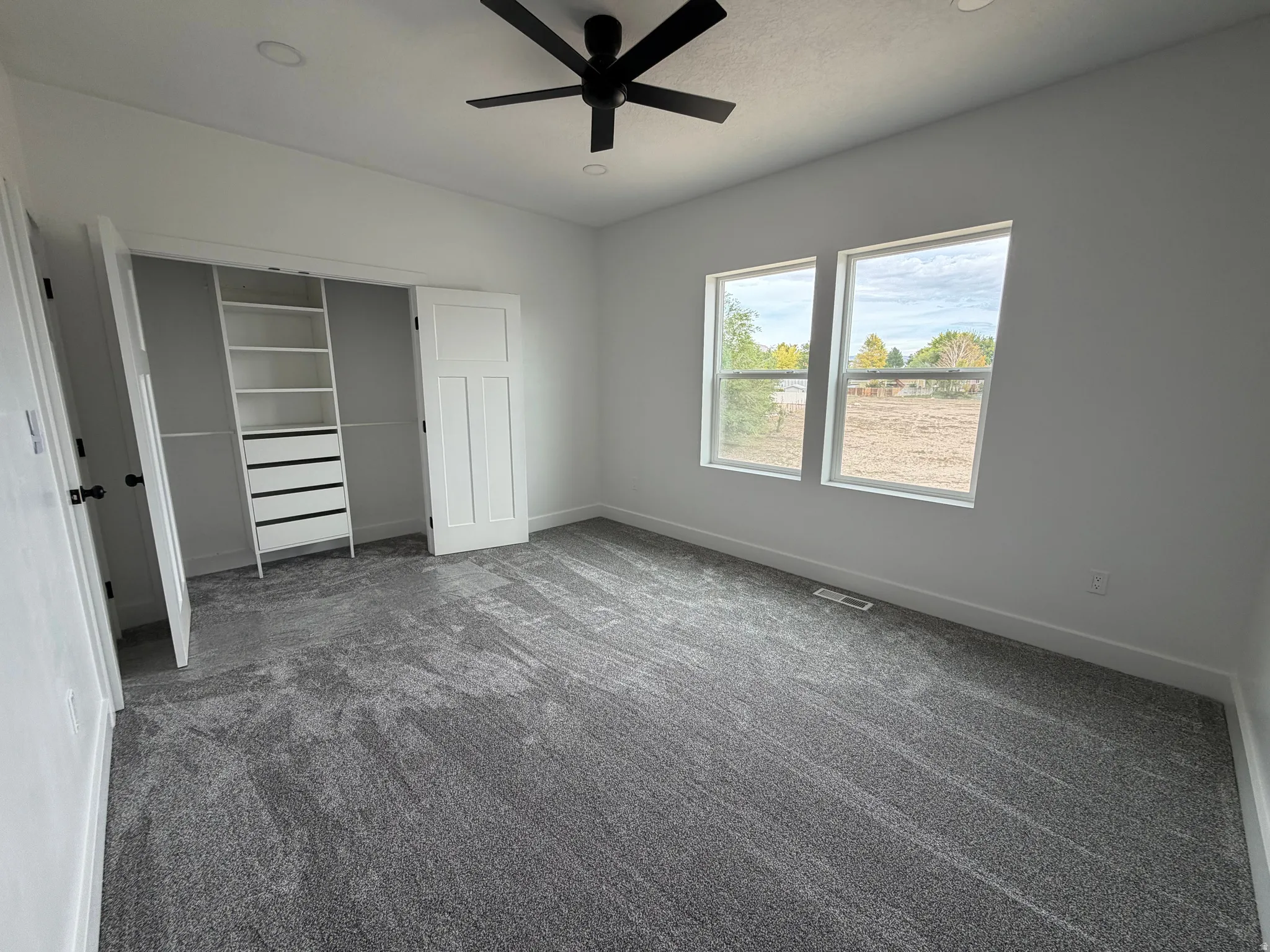 Bedroom 1 Recessed lighting, ceiling fan, built-in closet organization, two windows, and textured carpeting