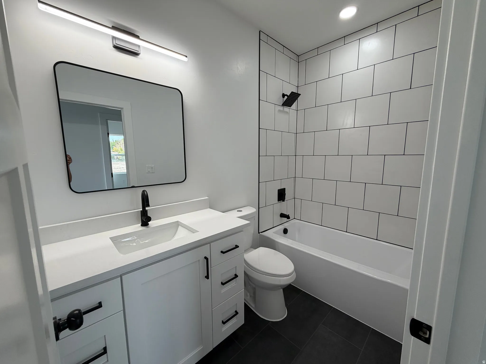 Upstairs Bathroom White subway tile shower surround with black grout, white vanity with an integrated sink, quartz countertop, and black hardware