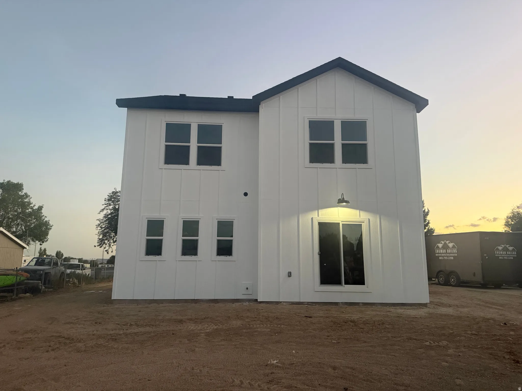 Two-story exterior with vertical white siding, multiple windows, and a sliding glass door