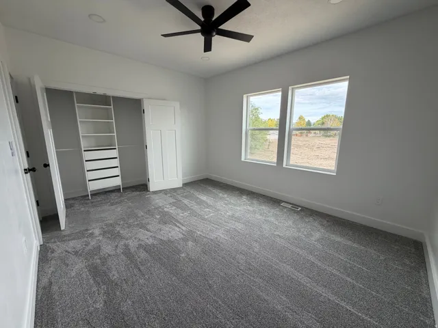 Bedroom 1 Recessed lighting, ceiling fan, built-in closet organization, two windows, and textured carpeting