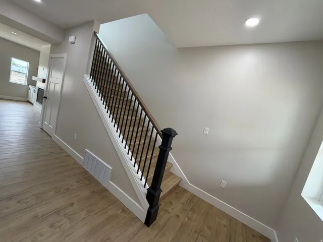 Wood-finish flooring throughout, with a staircase featuring black wrought iron balusters and a wood-finish handrail