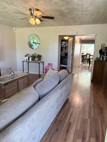 Wood-finish flooring throughout, ceiling fan with integrated lighting, and white paneled walls