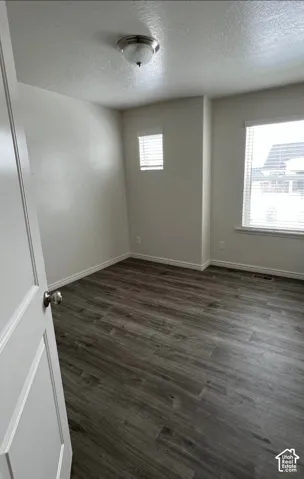 Wood-finish flooring, white walls, two windows with blinds, and a flush mount ceiling light fixture