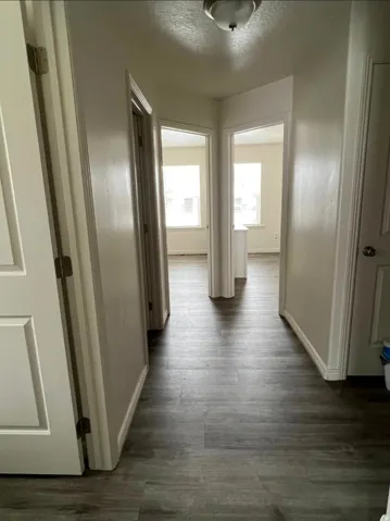 Hallway featuring wood-finish flooring and white trim