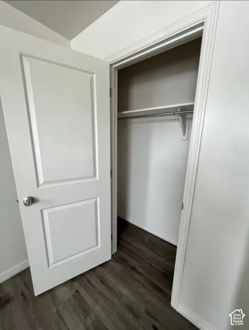 Paneled interior door with a brushed nickel knob, wood-finish flooring, and a built-in closet rod and shelf