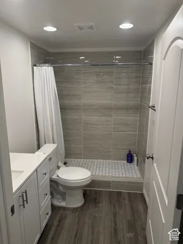 Shower with stone-finish wall tile, hex tile flooring, and a chrome shower rod