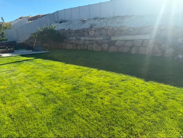 Expansive lawn with a stone retaining wall and a privacy fence
