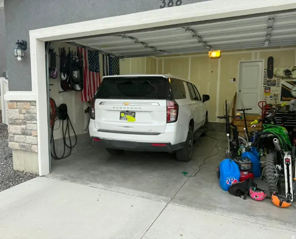 Attached garage with a concrete floor, finished interior walls, overhead lighting, and a service door