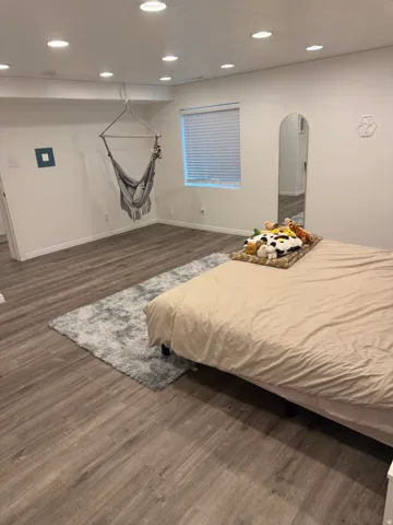 Recessed ceiling lighting, wood-finish flooring, and a window with blinds