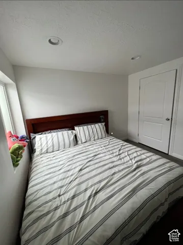 Recessed ceiling lighting, wood-finish flooring, white paneled interior door, and a single window