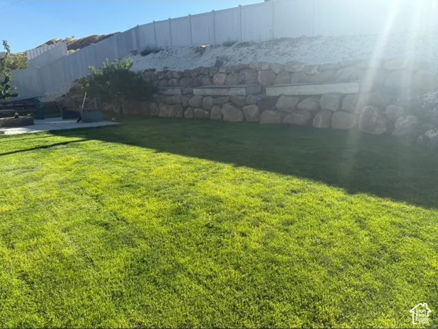 Expansive lawn with a stone retaining wall and a privacy fence