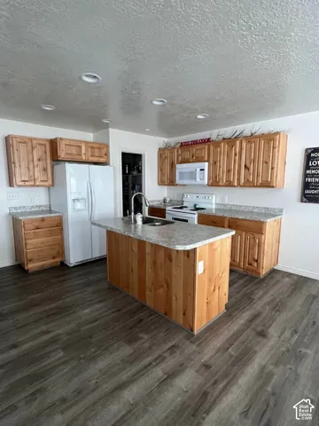 Kitchen featuring wood cabinetry, light-toned countertops, white appliances, recessed lighting, and wood-finish flooring
