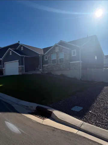 Two-story residence featuring a stone and siding facade, attached garage, and a sloped front lawn