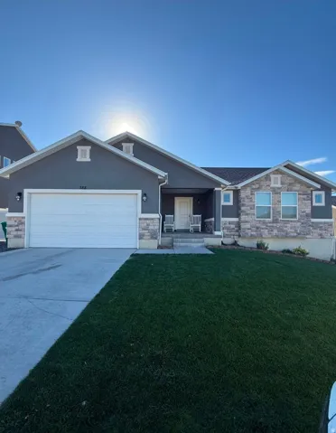 Contemporary residential exterior featuring a covered entry, attached two-car garage, stone veneer accents, and a concrete driveway