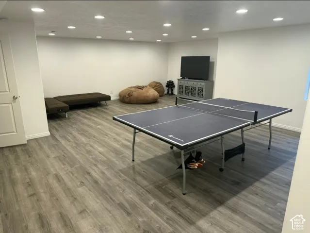 Spacious room with wood-finish flooring, recessed lighting, and white walls