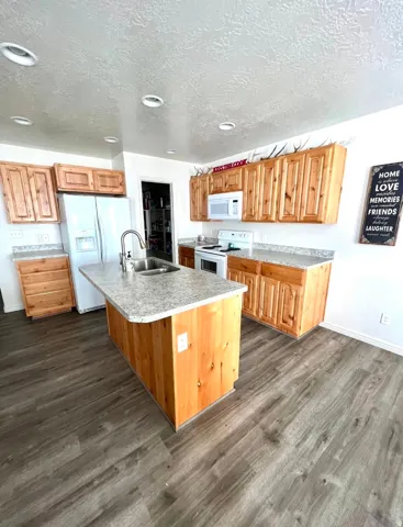 Kitchen featuring wood-finish cabinetry, light-toned countertops, and wood-finish flooring