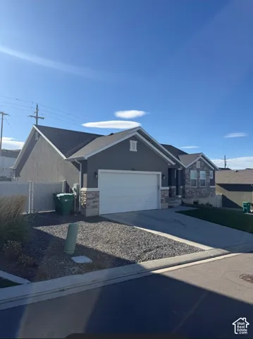 Stucco and stone exterior, attached garage, and a concrete driveway