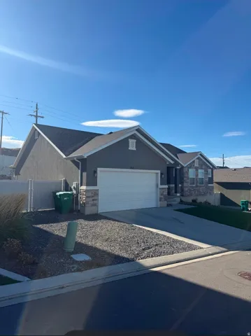 Stucco and stone exterior, attached garage, and a concrete driveway