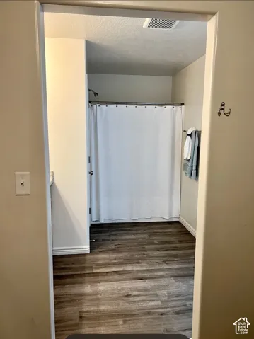 Wood-finish flooring leading to a shower area with a ceiling-mounted ventilation system