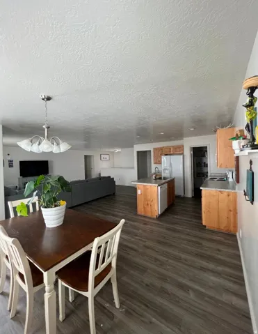 Wood-finish flooring throughout, kitchen island with built-in sink, stainless steel refrigerator, and wood cabinetry