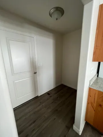 White paneled door, wood-finish flooring, recessed lighting, wood cabinetry, and granite-style countertop