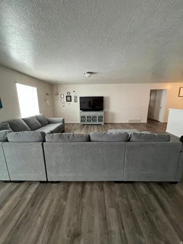 Wood-finish flooring throughout, light-toned walls, and a large window providing ambient light