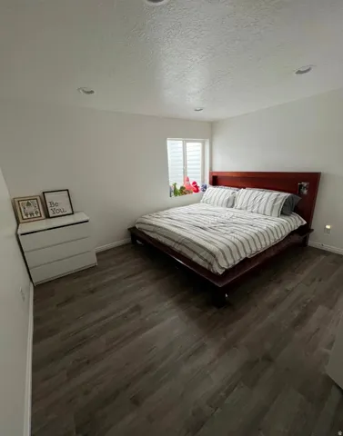 Wood-finish flooring throughout, recessed ceiling lighting, and a window with privacy blinds