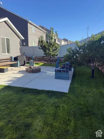 Expansive backyard featuring a manicured lawn, concrete patio, and a built-in fire pit