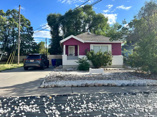 Vibrant exterior with a covered entry, white window trim, and a gravel front yard