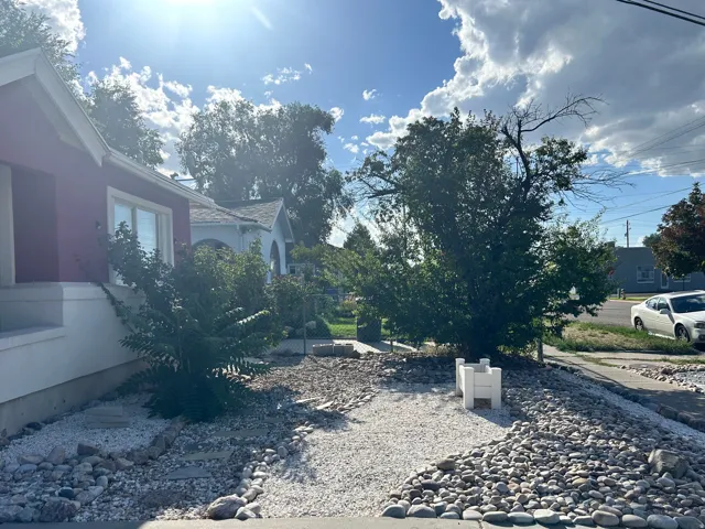 Crimson exterior with white trim, featuring a garden bed with white gravel, natural stone accents, and established plantings