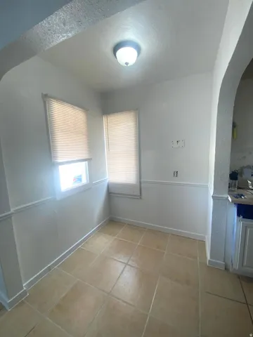 Tile flooring with integrated baseboards, paired with natural light from two windows, and a ceiling-mounted light fixture