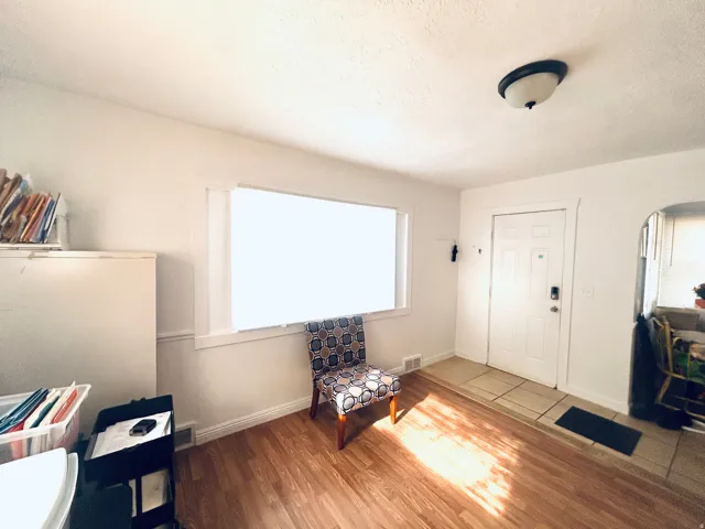 Wood-finish flooring, white trim, recessed window, flush-mount ceiling light, and a white paneled entry door with smart lock