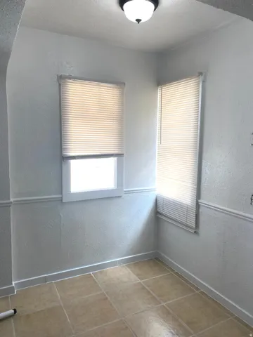 Corner room with tiled flooring and two windows