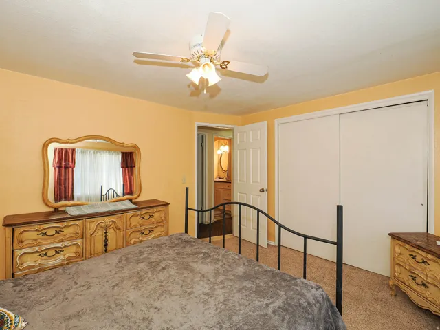 Ceiling fan with integrated lighting, sliding closet doors, and carpet flooring