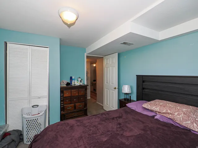 White louvered bifold closet doors, light blue wall paint, white interior door, and ceiling-mounted light fixture
