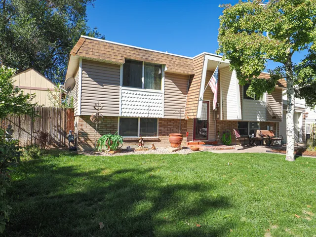 Split-level residence featuring a brick and siding exterior, a front patio, and a mature tree