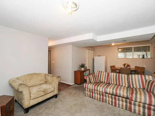 Recessed ceiling beam, surface-mounted ceiling light fixture, wall-to-wall carpeting, single window with blinds, and white painted walls