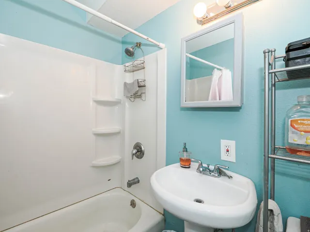 Bathroom featuring a pedestal sink, wall-mounted medicine cabinet, and a shower/tub combination