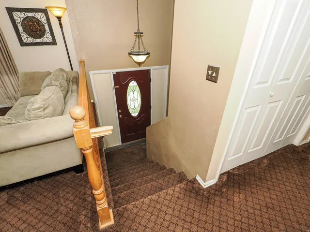 Staircase featuring patterned carpet, wood banister, and white baseboards