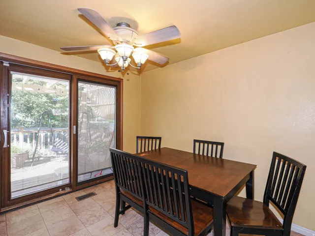 Tiled flooring, ceiling fan with integrated lighting, wood-framed sliding glass door, and exterior decking